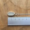 White oval seaglass necklace, set in silver. Shown against a ruler - approximately 18mm long.