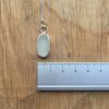 White oval seaglass necklace, set in silver. Shown against a ruler - approximately 8mm wide.