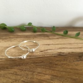 2 thin silver rings, each with a silver pebble attached.