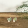 Two seaglass hearts set into silver to make a pair of studs. One is a light olive colour, the other a grey-green.