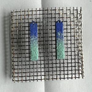 Two rectangular pieces f metal with blue and turquoise enamel powder on a gauze, ready to be fired.